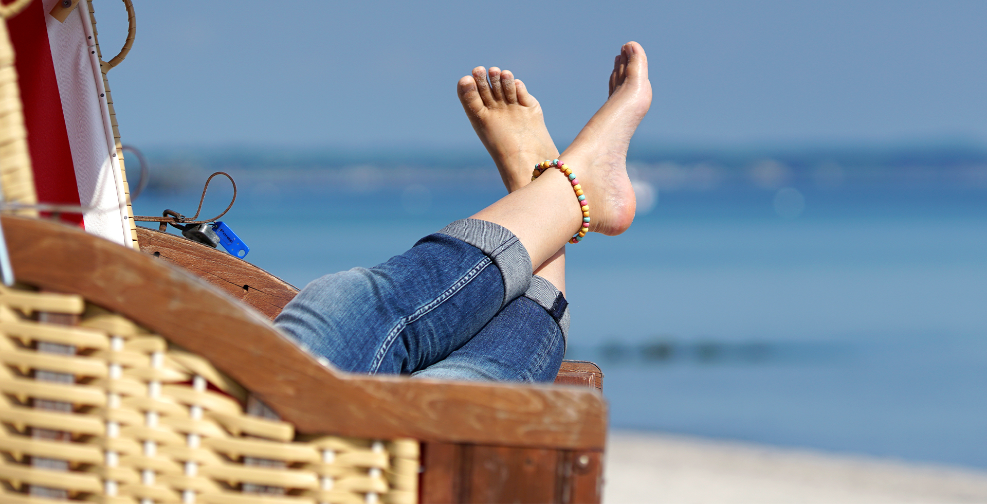 Frau liegt nach einer Fußreflexzonenmassage in einem Strandkorb am Ostsee-Strand. © Adobe Stock, Jenny Sturm